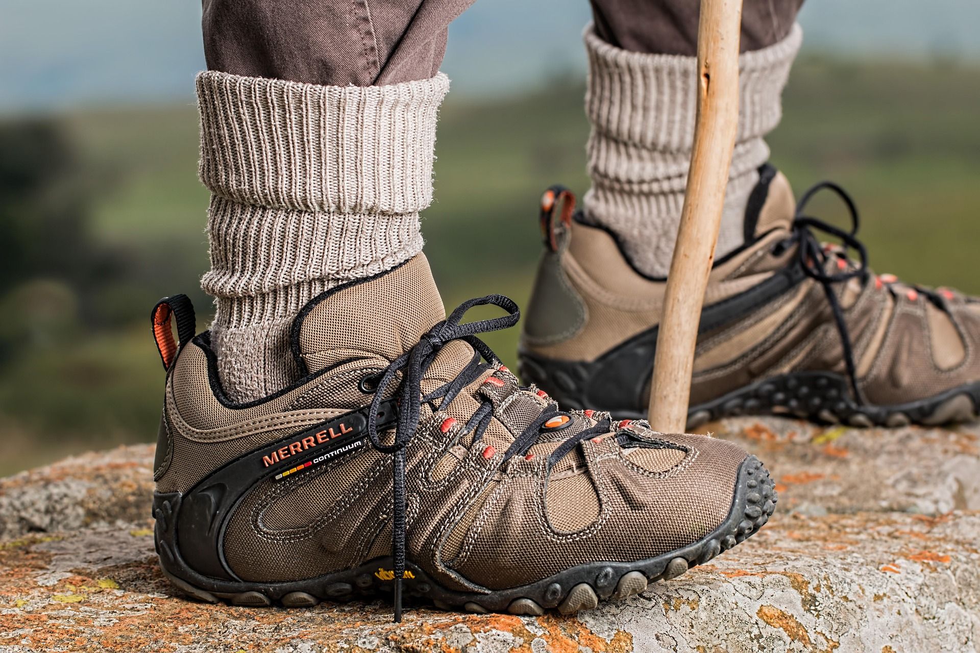 Close-up of a hiker's boots and walking stick on a rocky outcrop