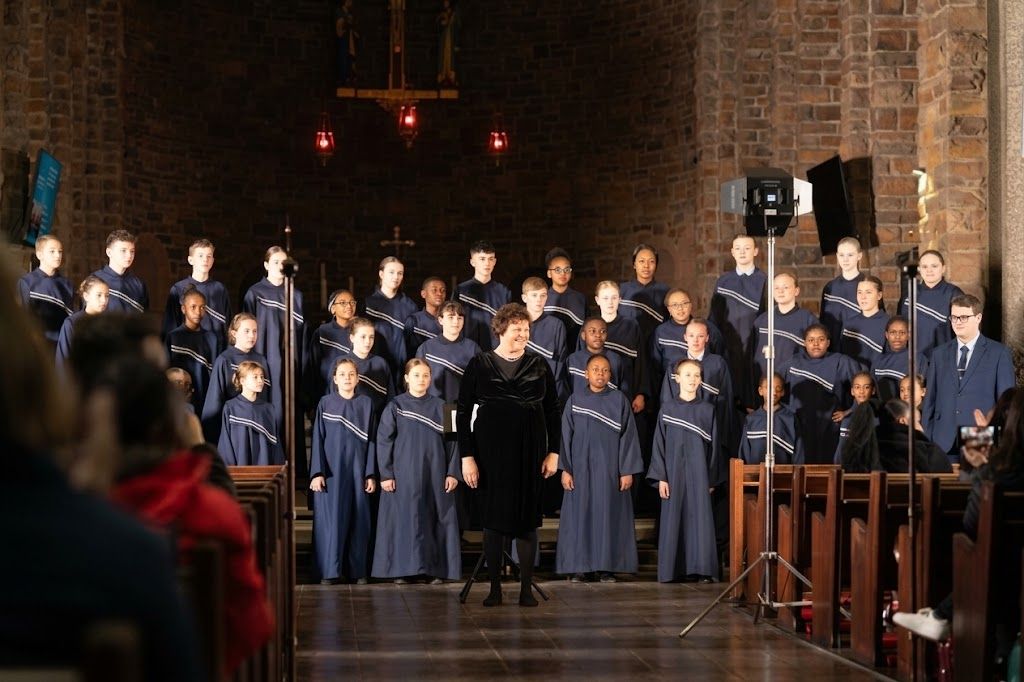 A children's choir in navy robes performing at a Sing for Smiles charity concert